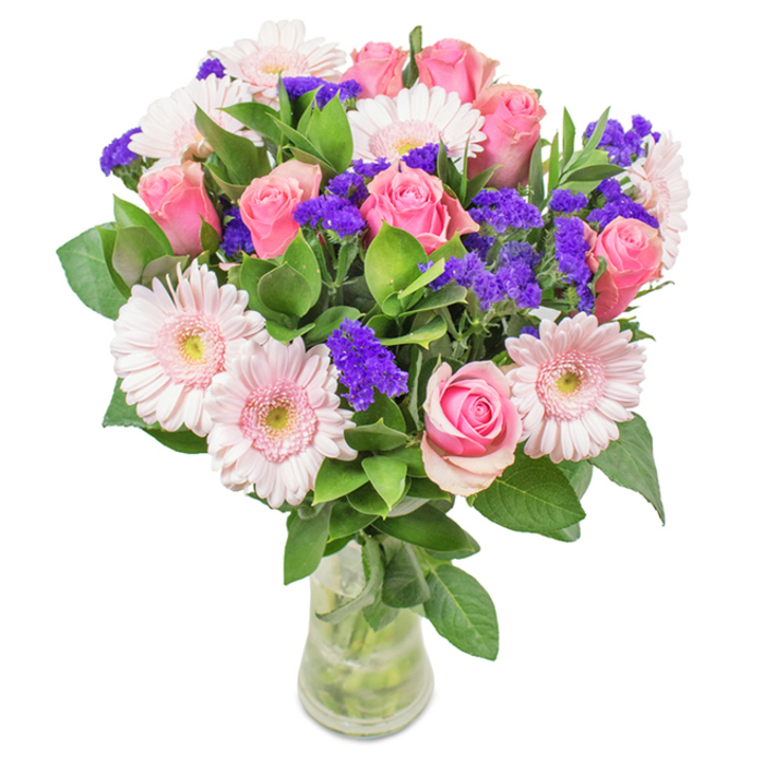 This polished bouquet, lovingly composed by an expert Belgravia florist, stands out against a crisp white backdrop in a slim glass vase that highlights each botanical detail. The array centres around about seven to nine soft and medium pink roses, their petals sculpted into classic spirals, some buds still shy and others showing a hint of full bloom. Five to seven pale pink gerbera daisies, with their round, showy faces and lighter central disks, brighten the arrangement while introducing gentle contrast. Interspersed vivid purple fillers-likely statice-add texture and a rich splash of colour, recalling the understated vibrancy of Belgravia's flower stalls. The base of deep, lush greens amplifies the vibrancy of the petals, each leaf bringing a cool, fresh energy to the design. Crystal-clear water and visible stems through the transparent vase emphasize the freshness and quality expected in Belgravia. Perfect for elevating special occasions-birthdays, anniversaries, Mother's Day-or as an artful accent in a refined Belgravia sitting room, this bouquet effortlessly conveys joy, admiration, and the affection of a stylish neighbourhood.